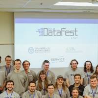 A group of students pose in front of the DataFest logo